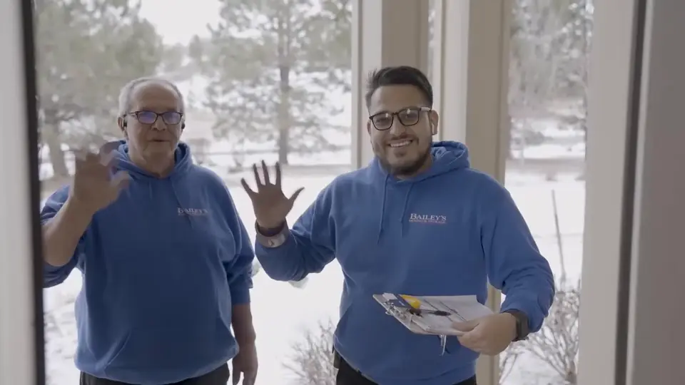 Two Bailey's Moving & Storage movers waving at a customer's front door
